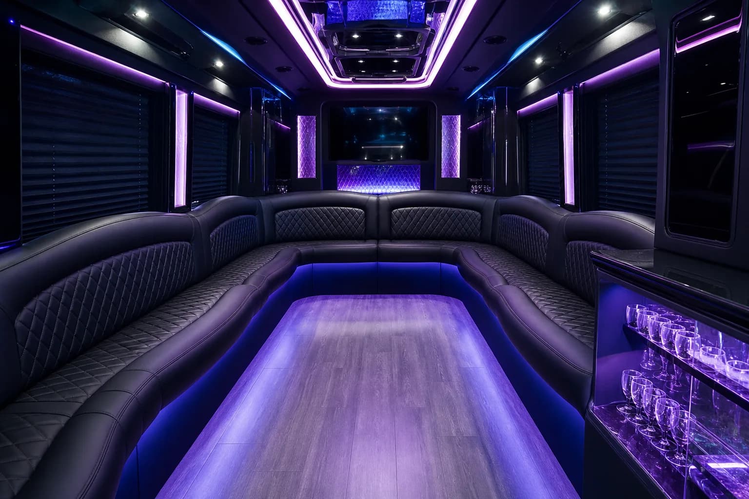 Party bus cabin lit in purple with a glowing floor running down the aisle
